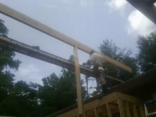 Carpenter setting a ridge beam over a new addition frame — Ice Dam Removal by Roofing Brothers in Van Meter