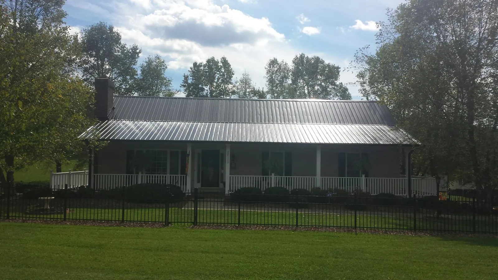 Gray metal roof on a brick ranch with a full width front porch — Gutter Guard Installation work by our crew in Van Meter