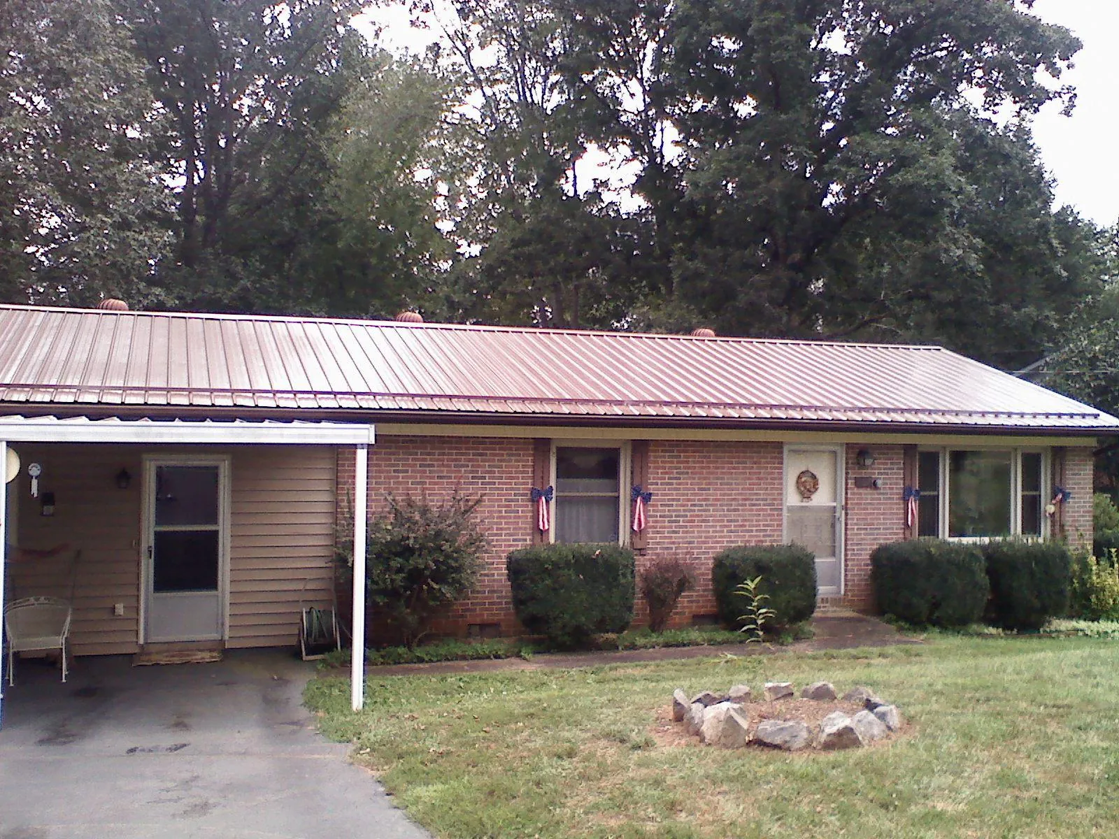 Bronze metal roof and carport on a brick ranch home — Roof Repair work by our crew in Van Meter