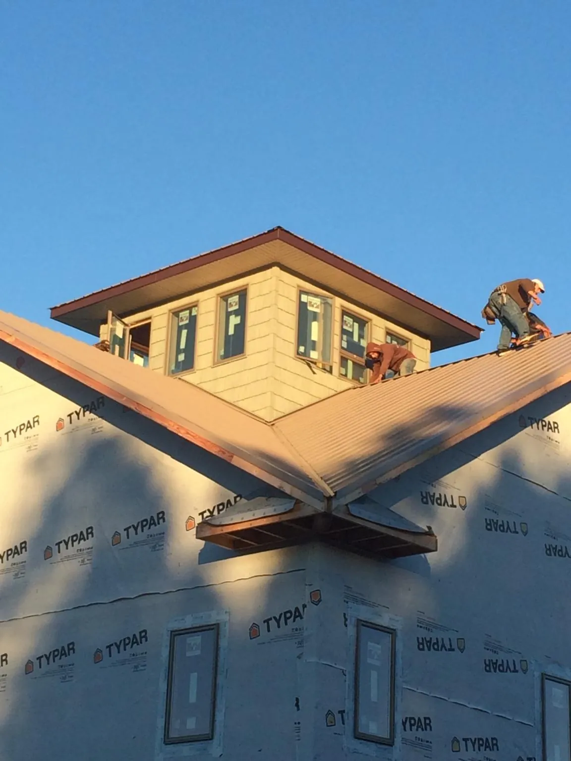 Roofers working around a rooftop cupola on a new metal roof at sunset — Roof Waterproofing in Van Meter by Roofing Brothers
